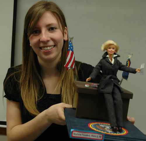 Kate Reeves, displaying a Mme. Barbie President by fellow journalism student Cami Stephenson, conducted research on gender bias in New York Times editorials.